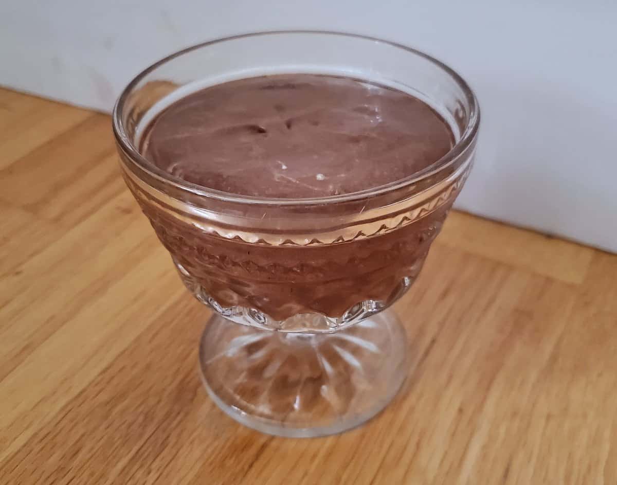 Image shows A glass of bourbon chocolate mousse sitting on a wooden table.