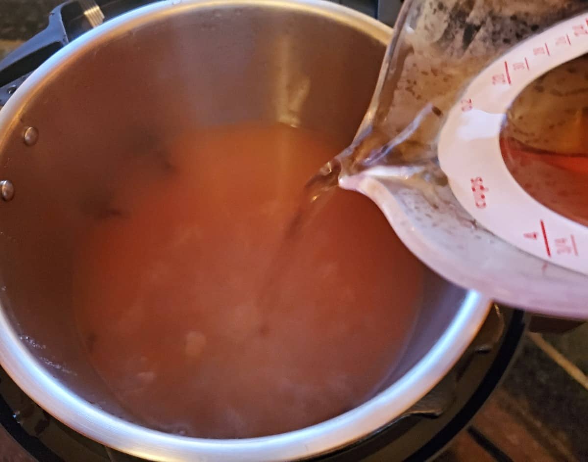Adding rum to spiked apple cider in a pot.