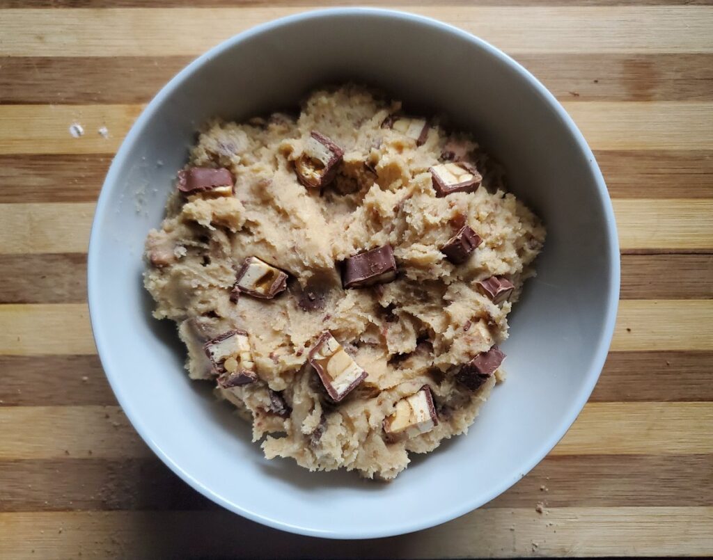 Overhead shot of edible candy bar cookie dough in a white bowl.