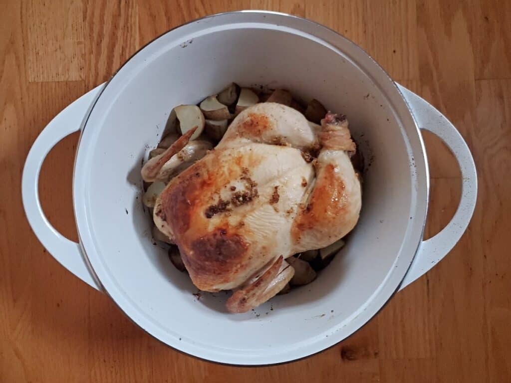 Perfect lemon roast chicken in a white dutch oven.