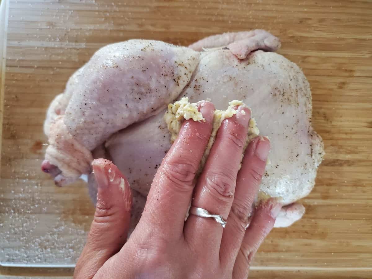 Rubbing butte on skin of chicken.