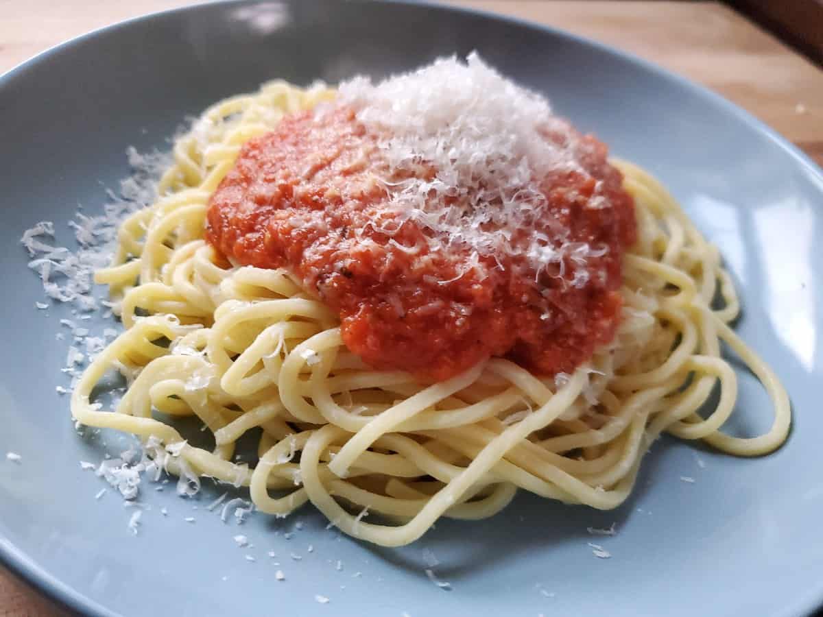 Wildgrain fresh pasta on a blue plate with sauce and cheese on top.