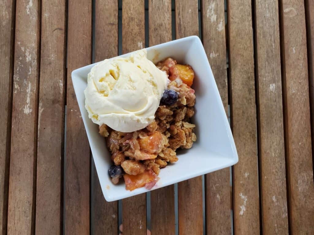 Overhead shot of blueberry peach crisp with ice cream.
