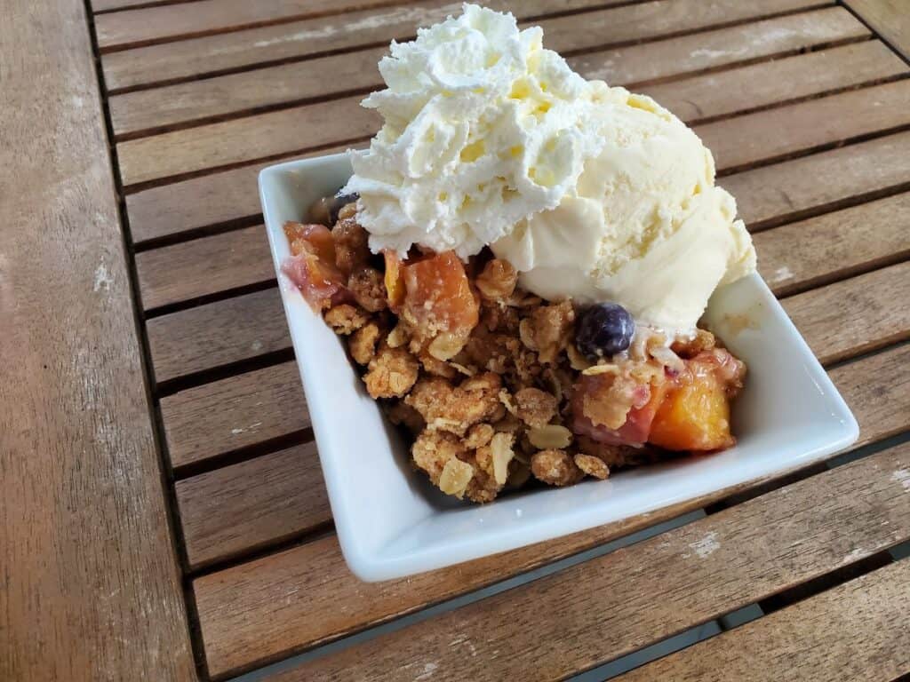 Peach crisp with ice cream and whipped cream.