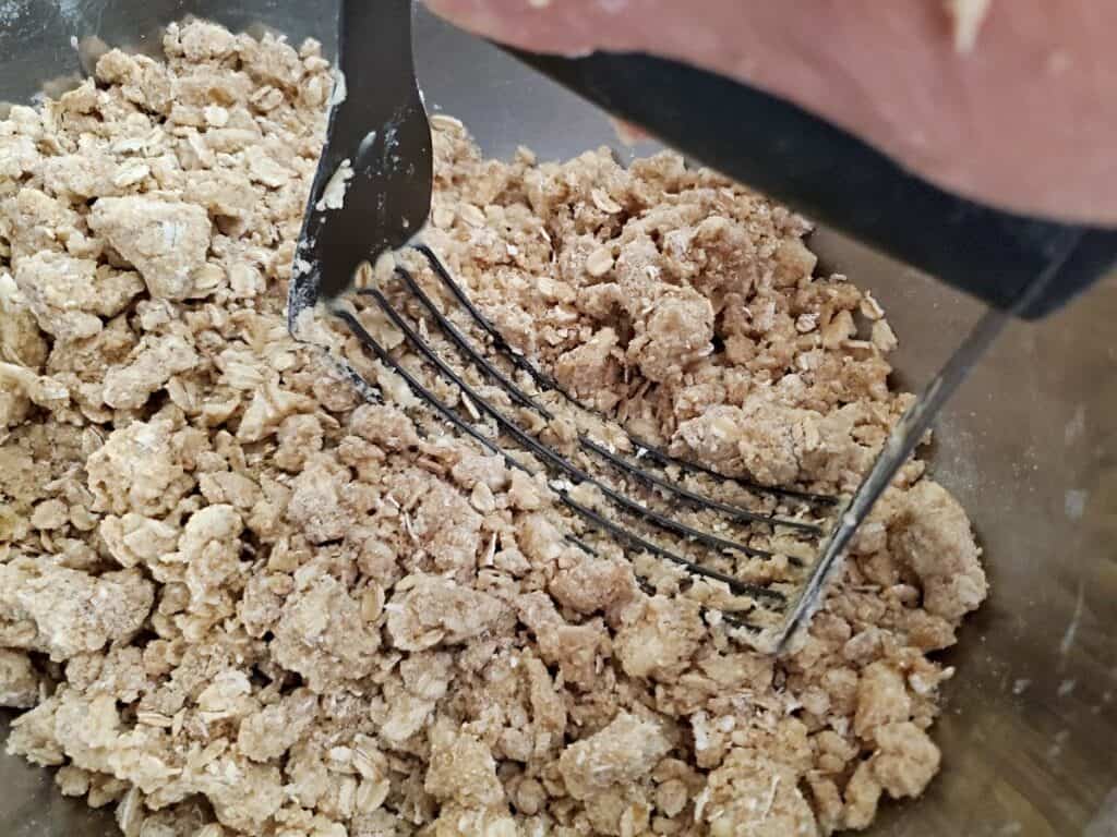 Crumb bar dough with a pastry cutter.