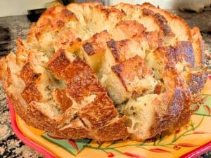 Image shows cheesy Garlic Pull-Apart Bread served on a plate.