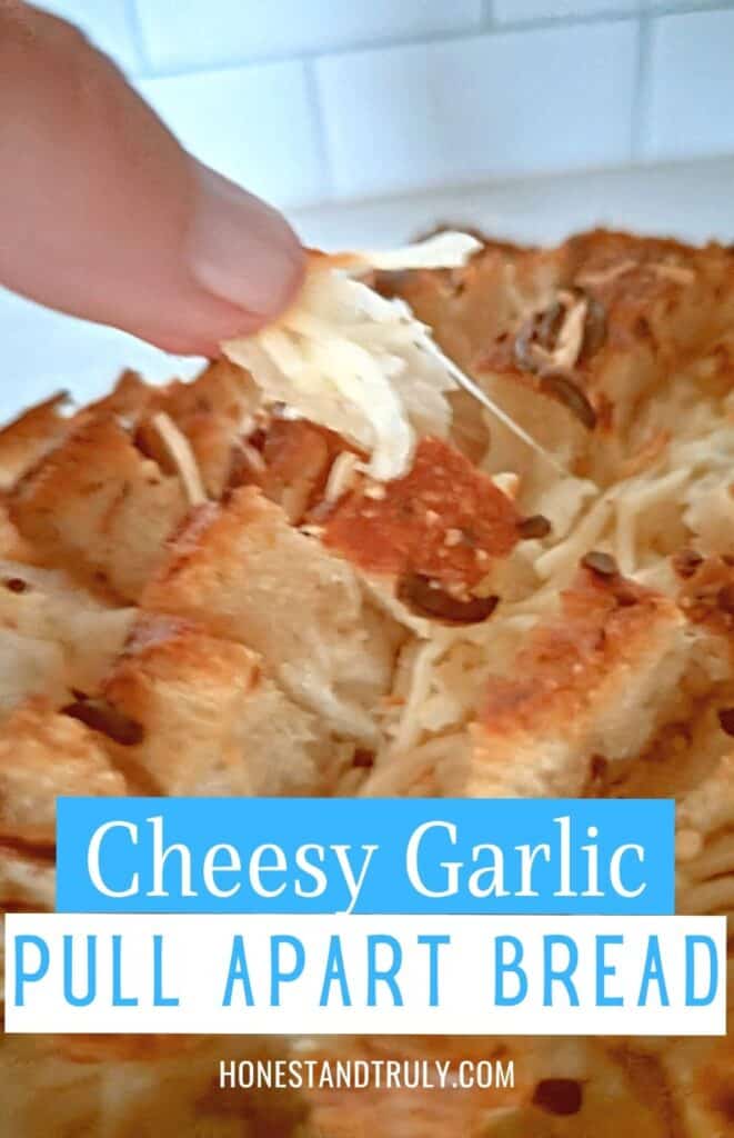 Hand pulling off a piece of cheesy garlic bread with text cheesy garlic pull apart bread.