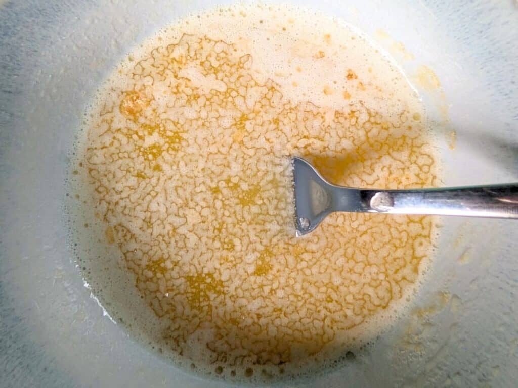 Image shows a melted butter and minced garlic in a bowl.