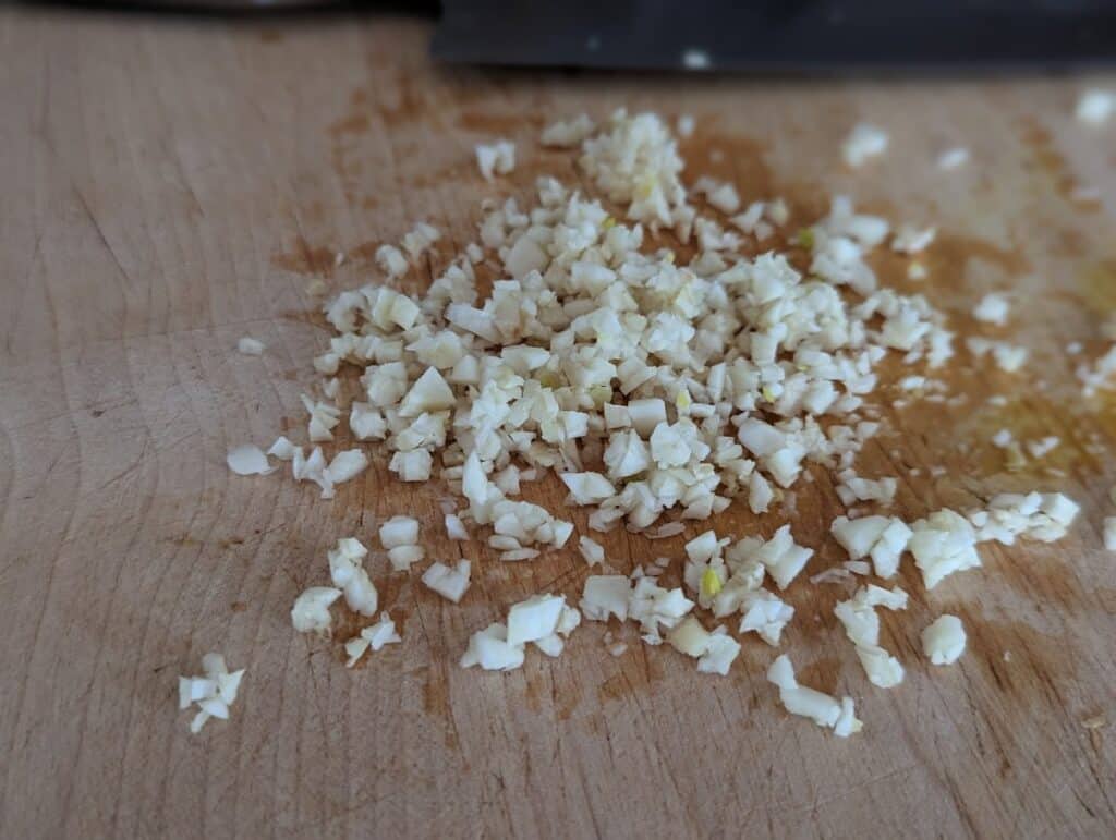 Photo of minced garlic on a cutting board.