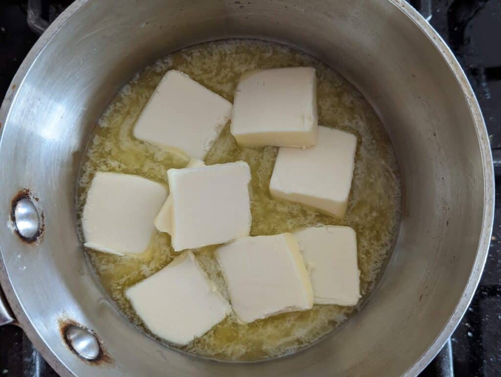 Pats of butter melting in a metal pot.
