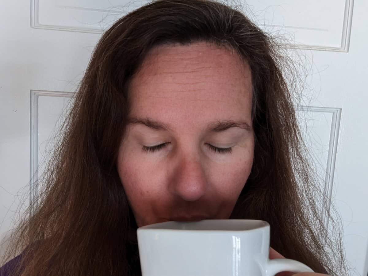 Person sipping a drink with their eyes closed.