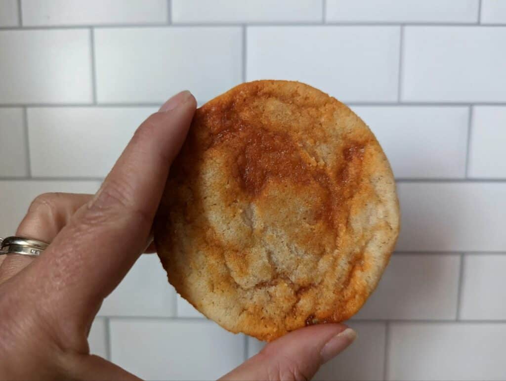 Hand holding a spicy caramel cookie against a subway tile background.