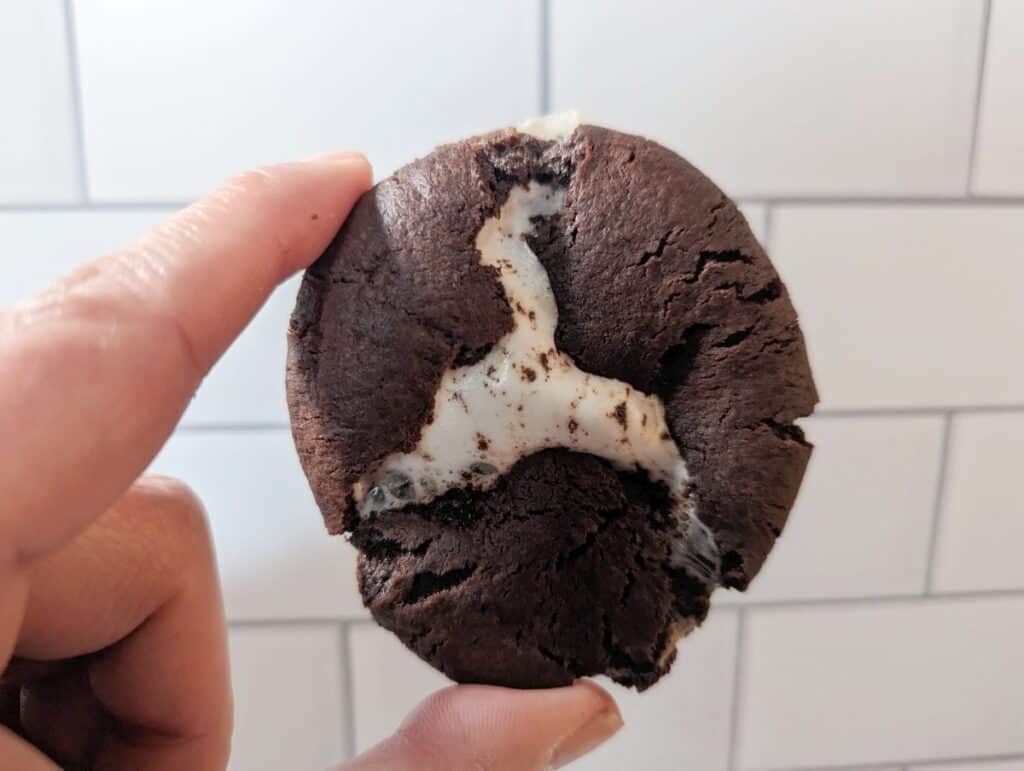 Chocolate marshmallow cookie held in front of subway tile.