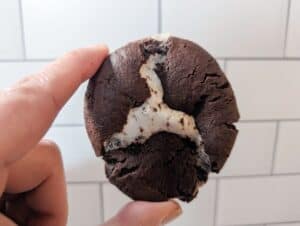 Chocolate marshmallow cookie held in front of subway tile.