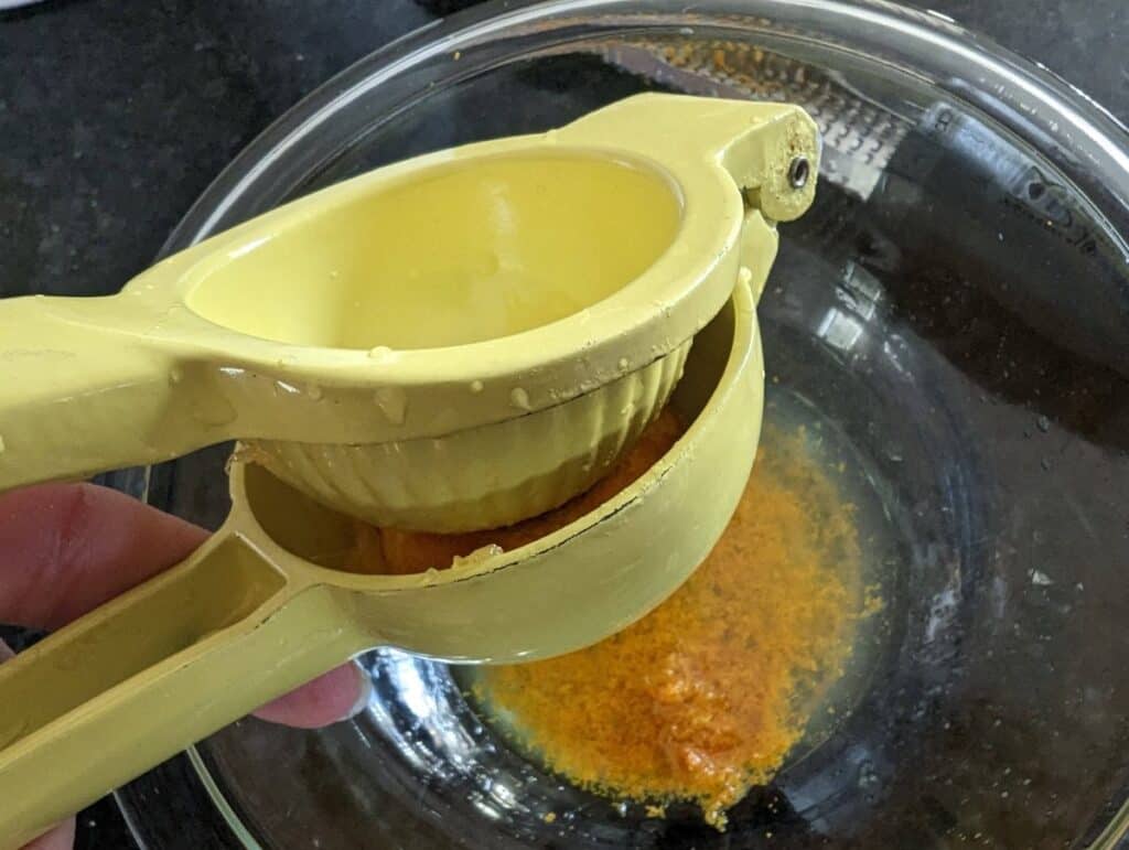 Juicing an orange into a bowl with zest.