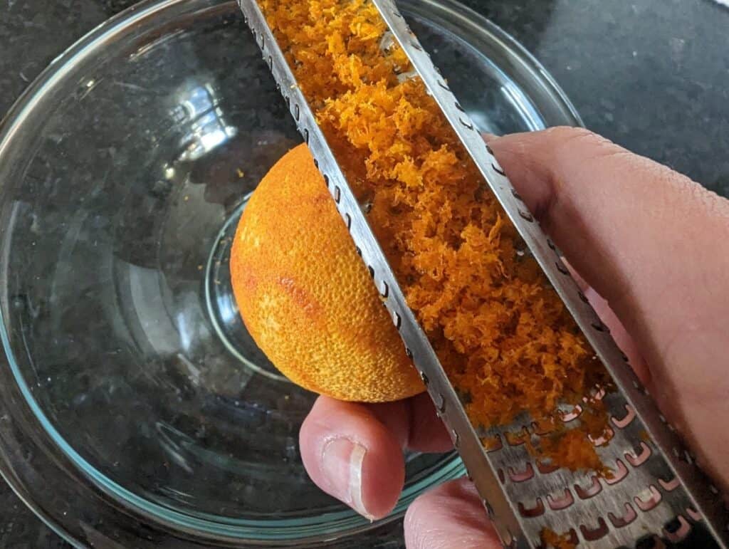 Zesting an orange into a bowl.