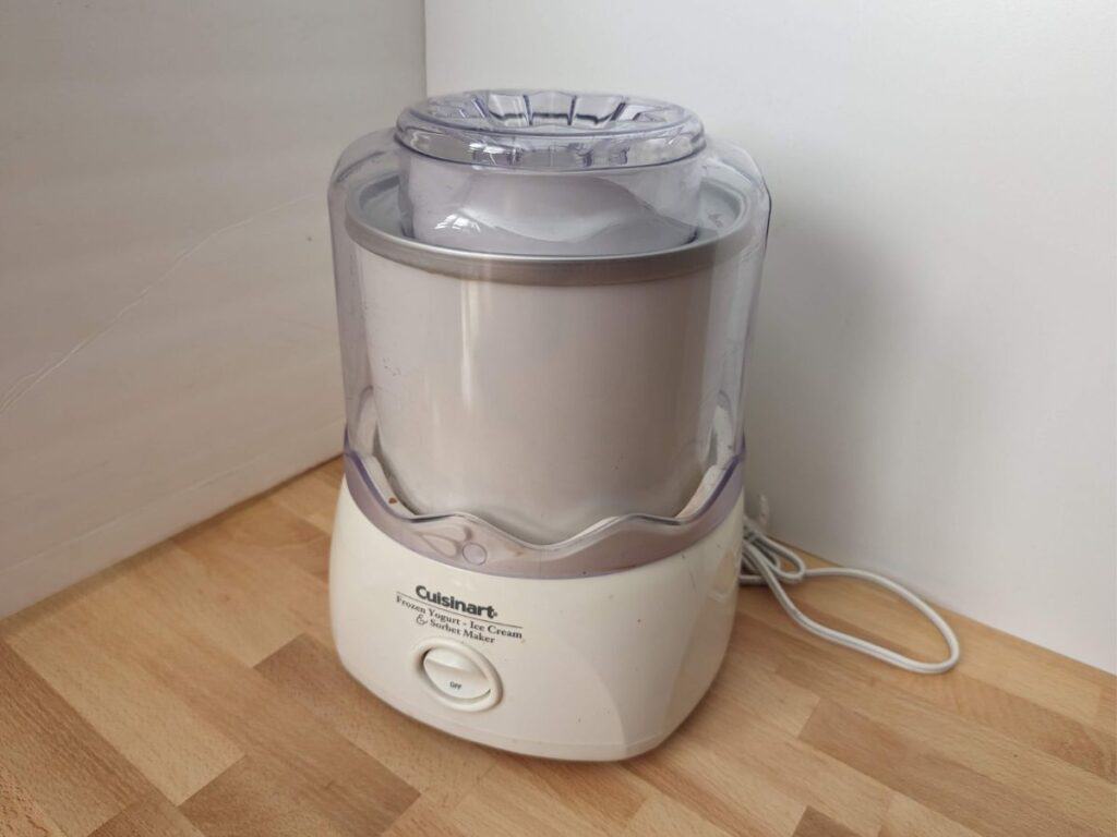 Image shows a Cuisinart ice cream maker on a wooden table.