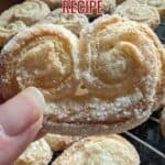 Image shows a Hand holding a palmier with text the best palmiers recipe.