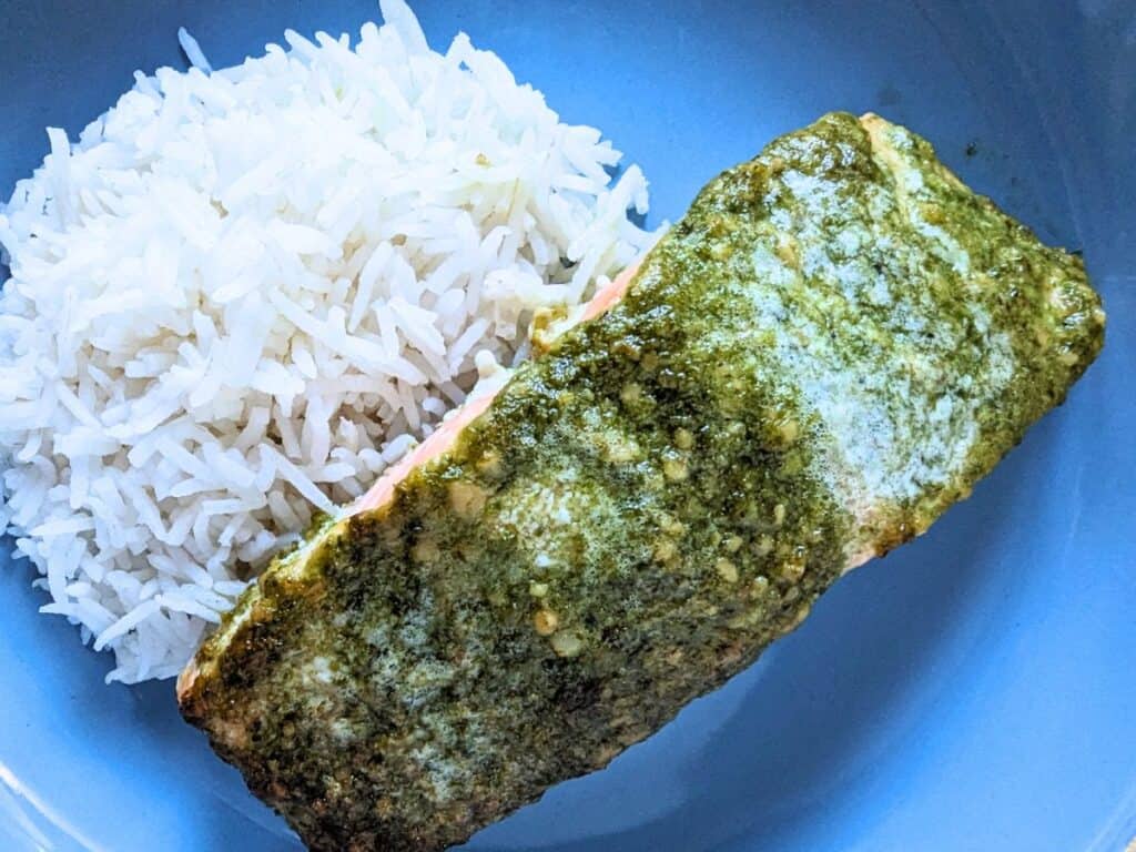 Image shows an Overhead of Pesto salmon on a blue plate.