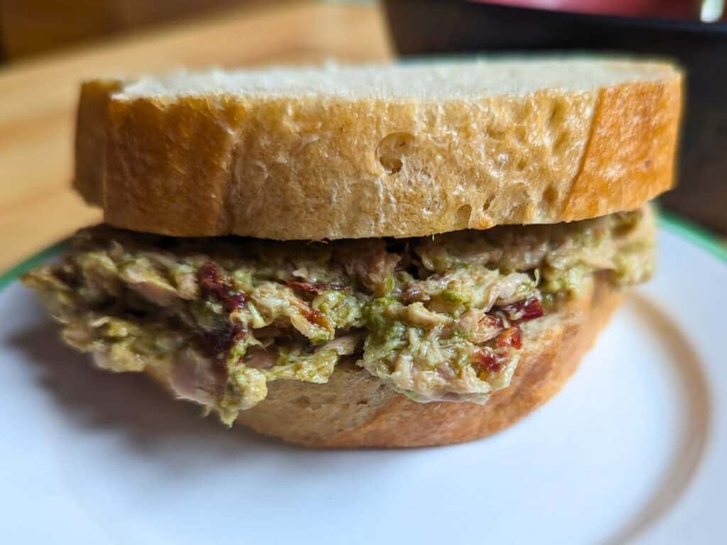 Image shows front facing sundried tomato pesto tuna sandwich on a plate.