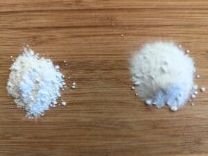 Image shows Baking soda and baking powder on a wooden cutting board in small piles.