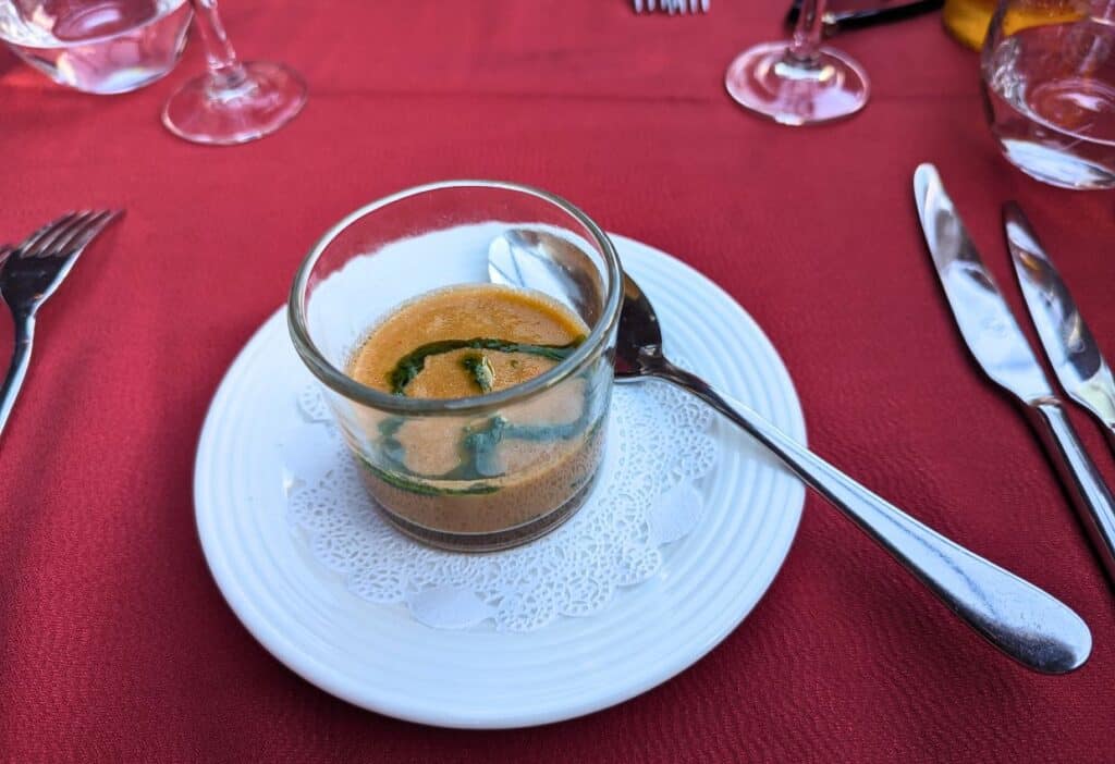 Image shows a Glass filled with a chilled soup on a table.