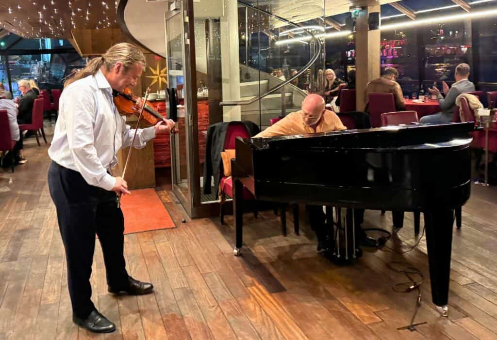 Image shows Piano and violin players on a boat.