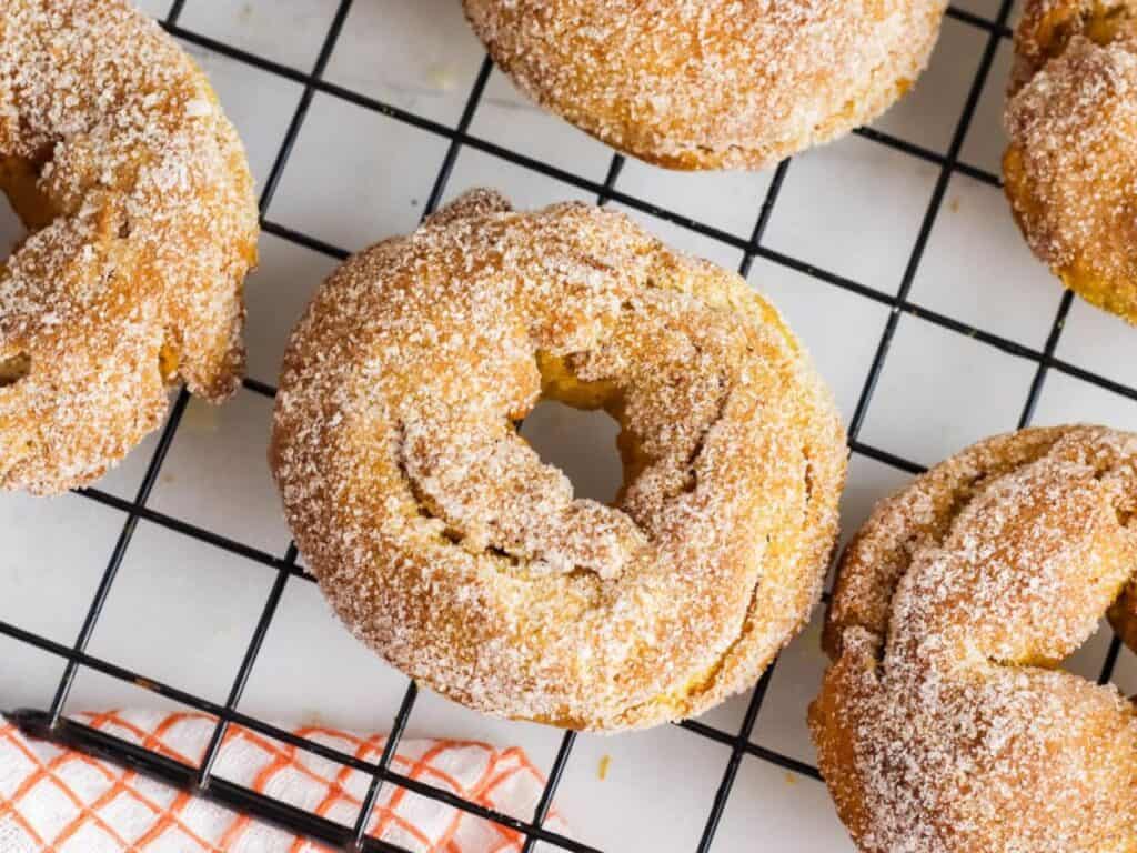 Image shows air fryer pumpkin donuts on a cooling rack,