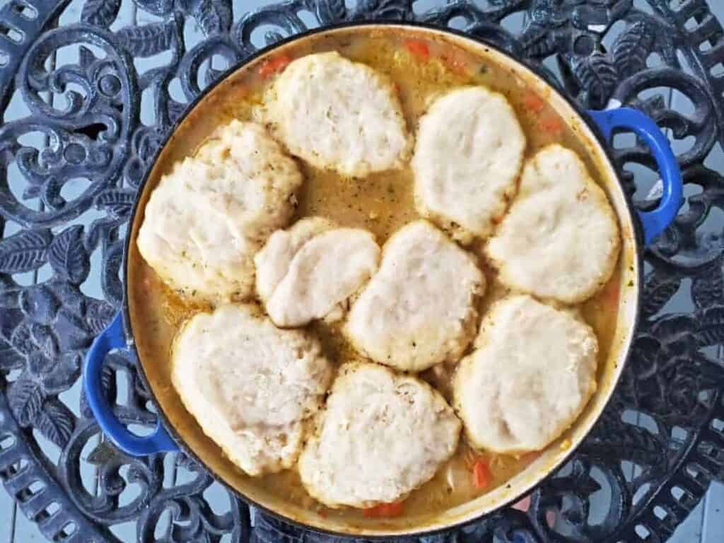 Image shows chicken stew with biscuits served in a pot.