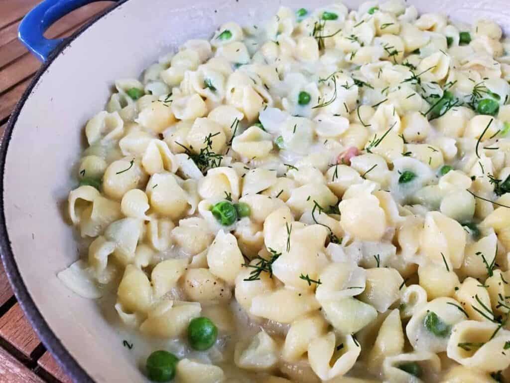 Image shows close up of creamy pea pasta with dill in a pot.