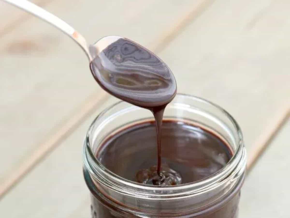Image shows A spoon is pouring espresso hot fudge sauce into a jar.
