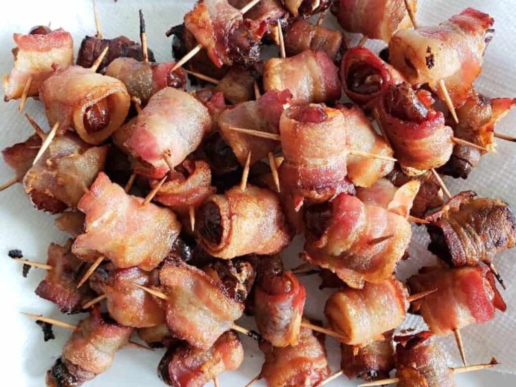Image shows delicious bacon wrapped dates piled together.