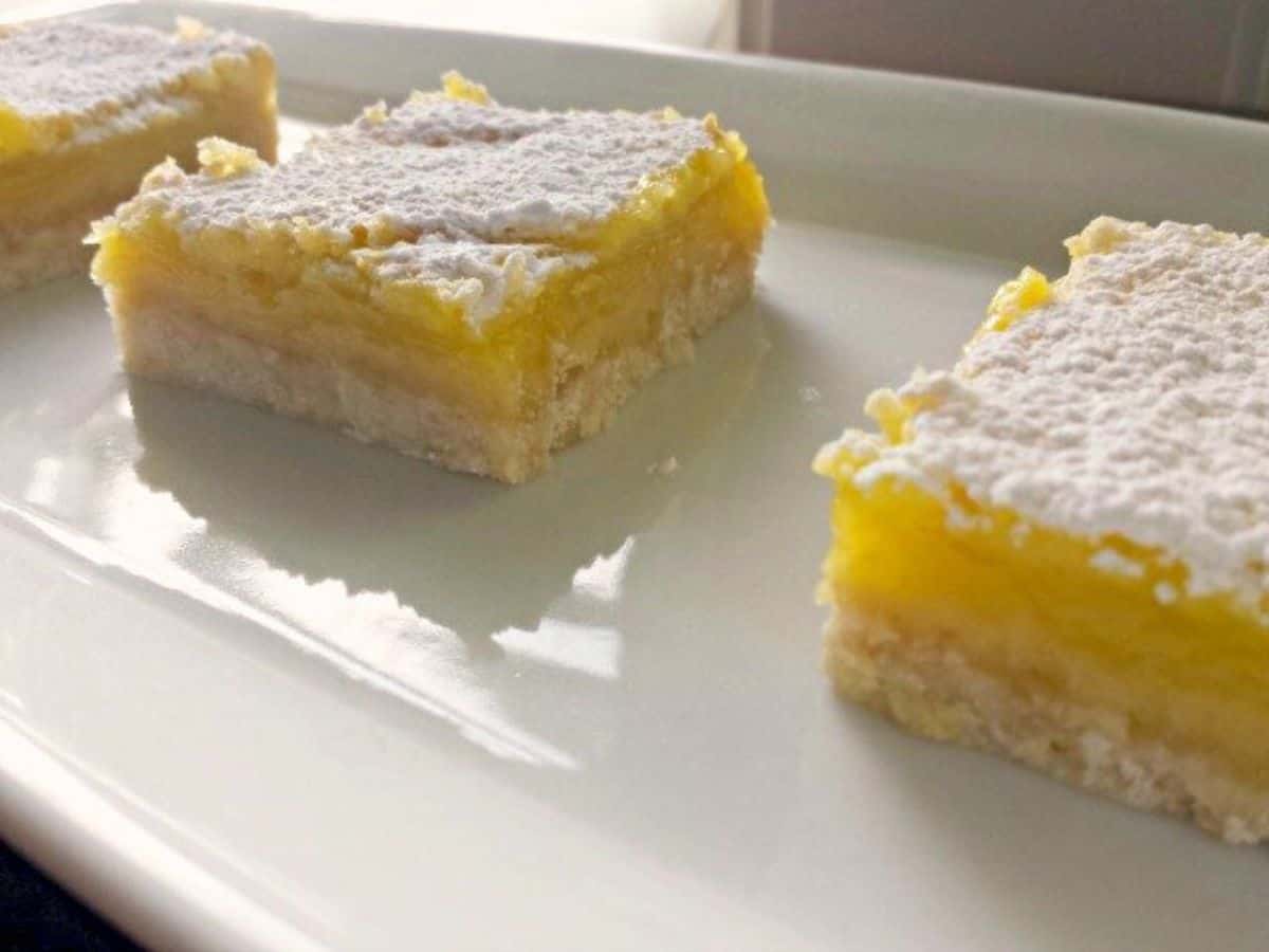 Image shows a close up of Lemon Squares on a white plate.