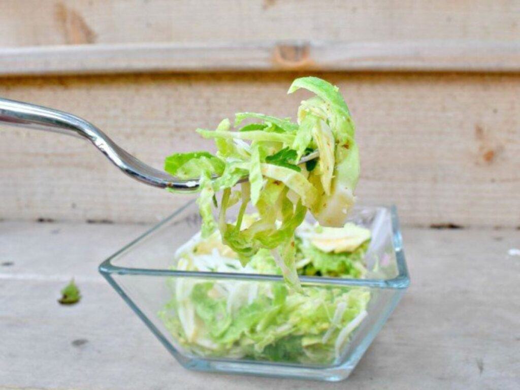 Image shows delicious shaved brussel sprout salad on a fork.