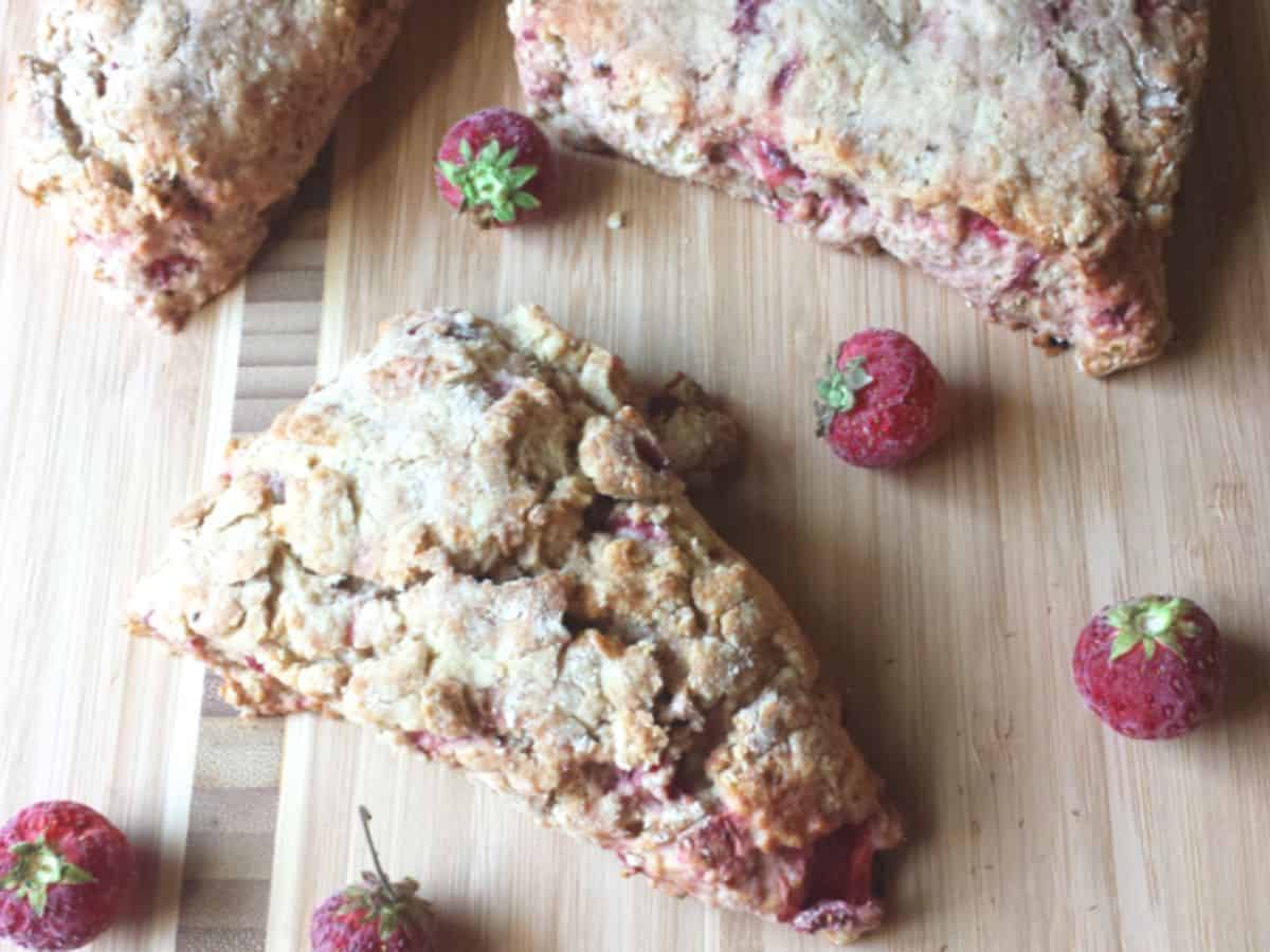 Image shows an overhead shot of Strawberry bacon scones on a wooden cutting board.