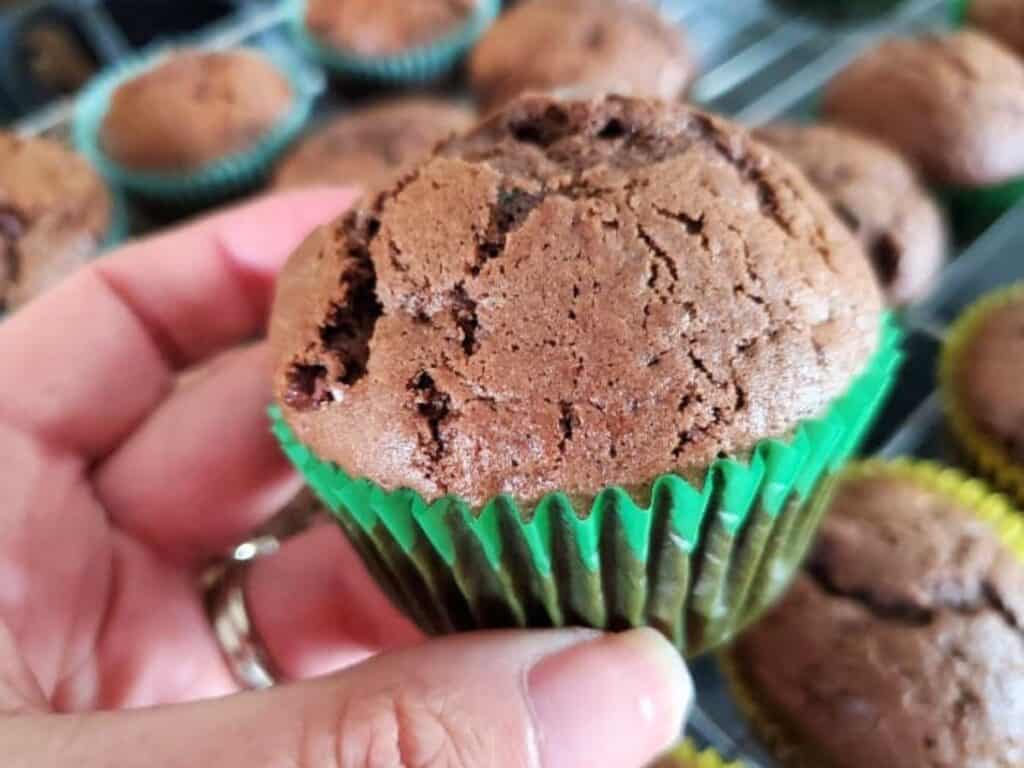 Image shows holding a single piece of double chocolate zucchini muffin.