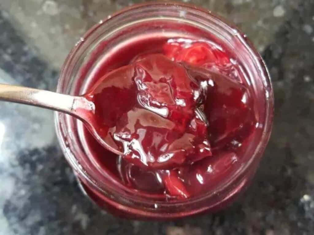 Image shows homemade cherry syrup scooped using a spoon.