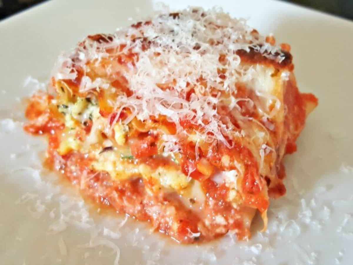 Image shows a lasagna roll up on a white plaet.