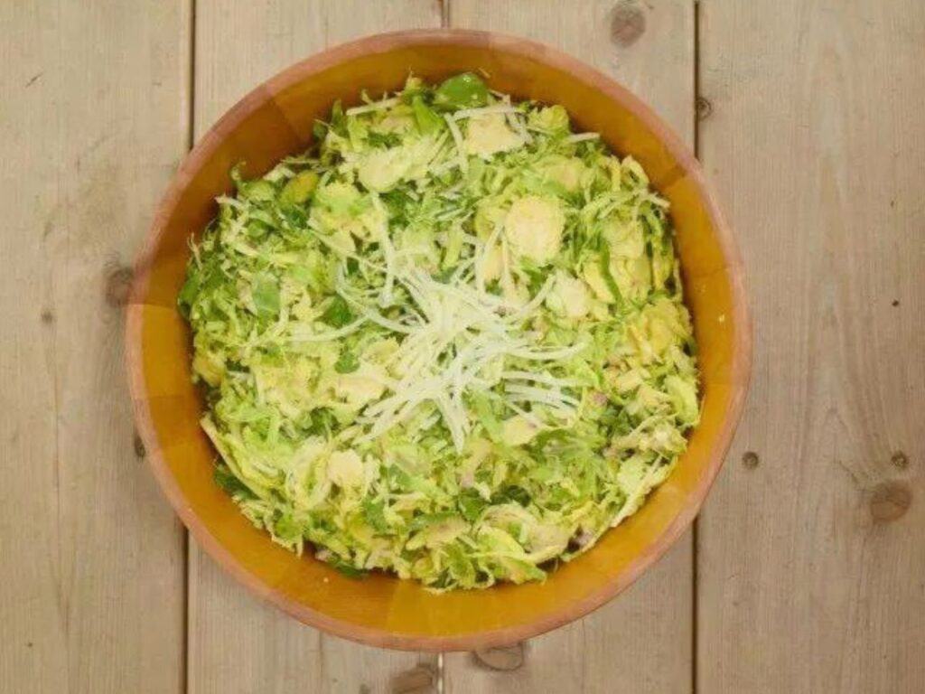 Image shows raw shaved brussels sprouts salad in a bowl.