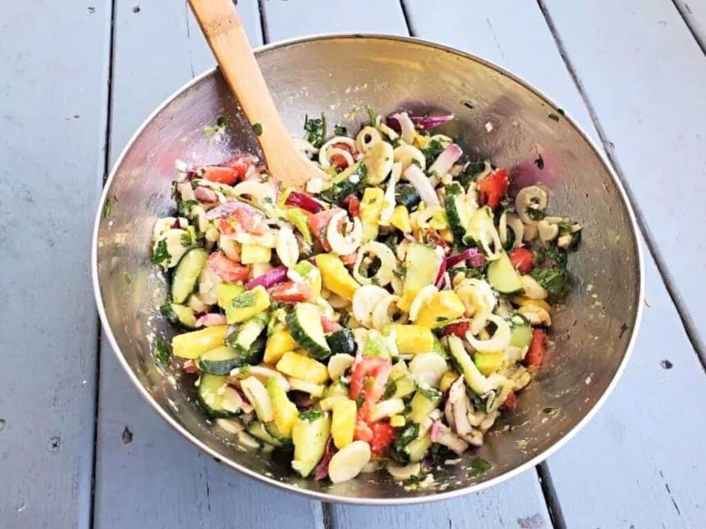 Image shows ready to serve hearts of palm salad in a metal bowl.