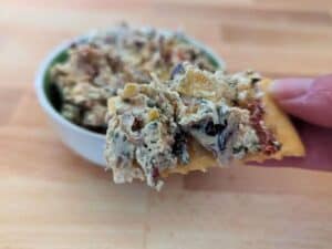 Image shows yummy bite of Tuscan artichoke and sundried tomato dip.