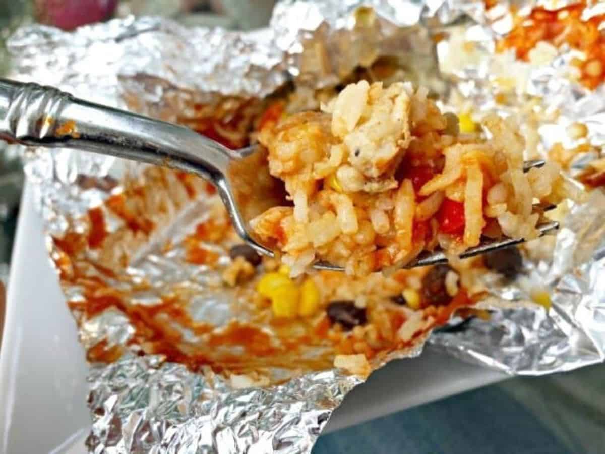 Grilled chicken foil packet with a fork holding a serving.