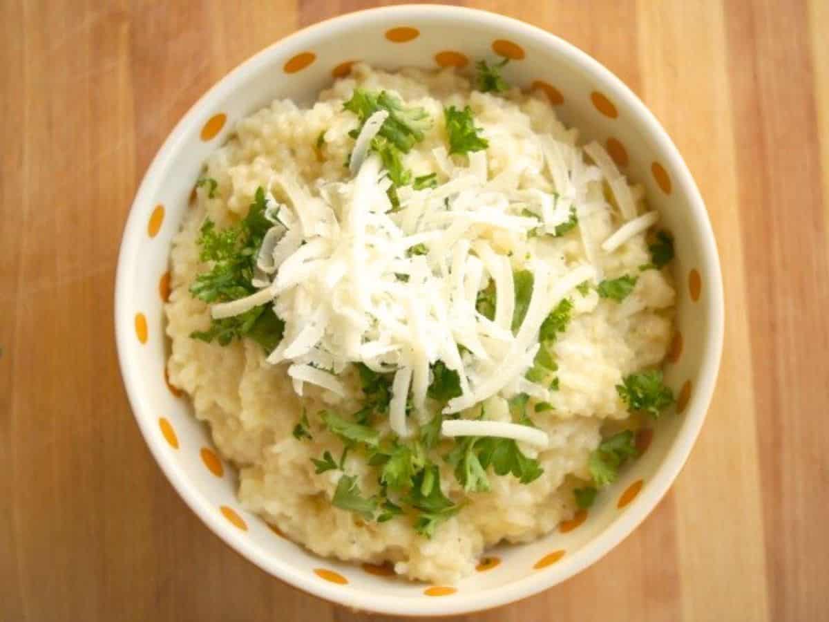 Image shows Chicken and pea risotto on a spoon with more in a green bowl behind it.