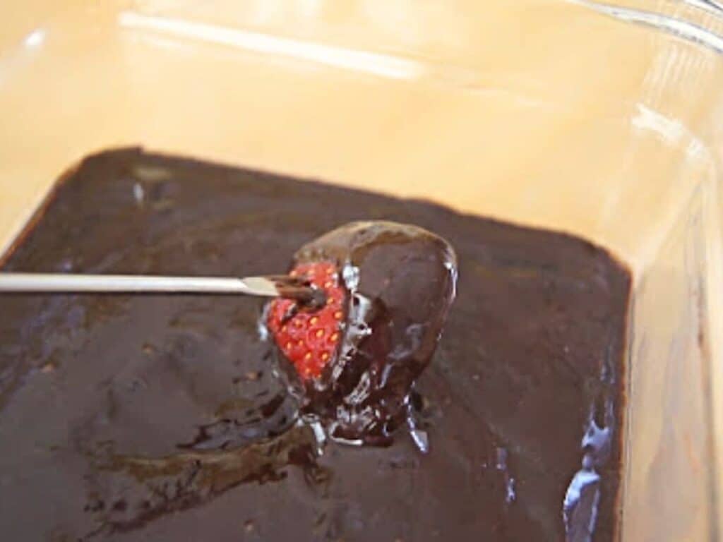 Image shows dipping strawberry into irresistible chocolate fondue.