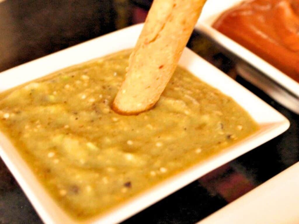 Image shows dipping taquitos in easy to make roasted tomatillo salsa.
