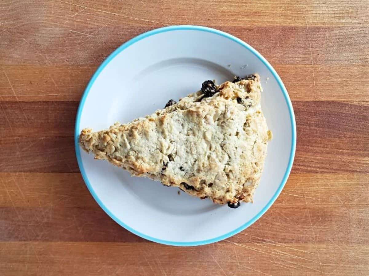 Image shows a buttermilk raisin scone on a plate.