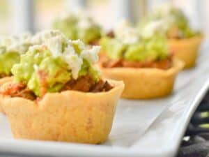 Image shows irresistible crockpot Mexican beef in masa cups.