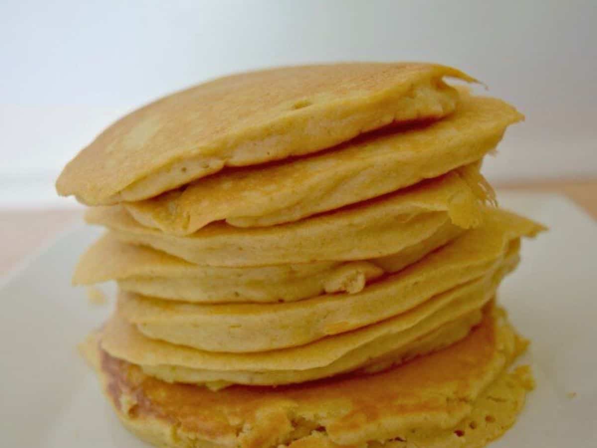 Image shows a close up of a stack of Oatmeal Pancakes on a white plate.