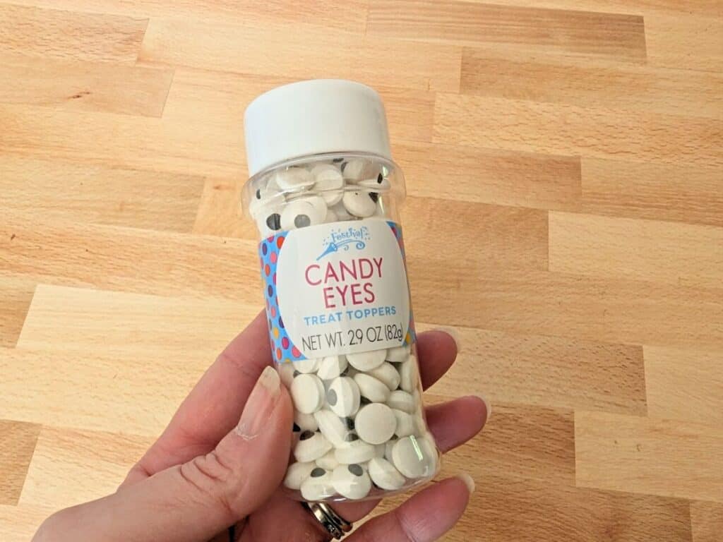 Image shows aHand holding a bottle of candy eyes.