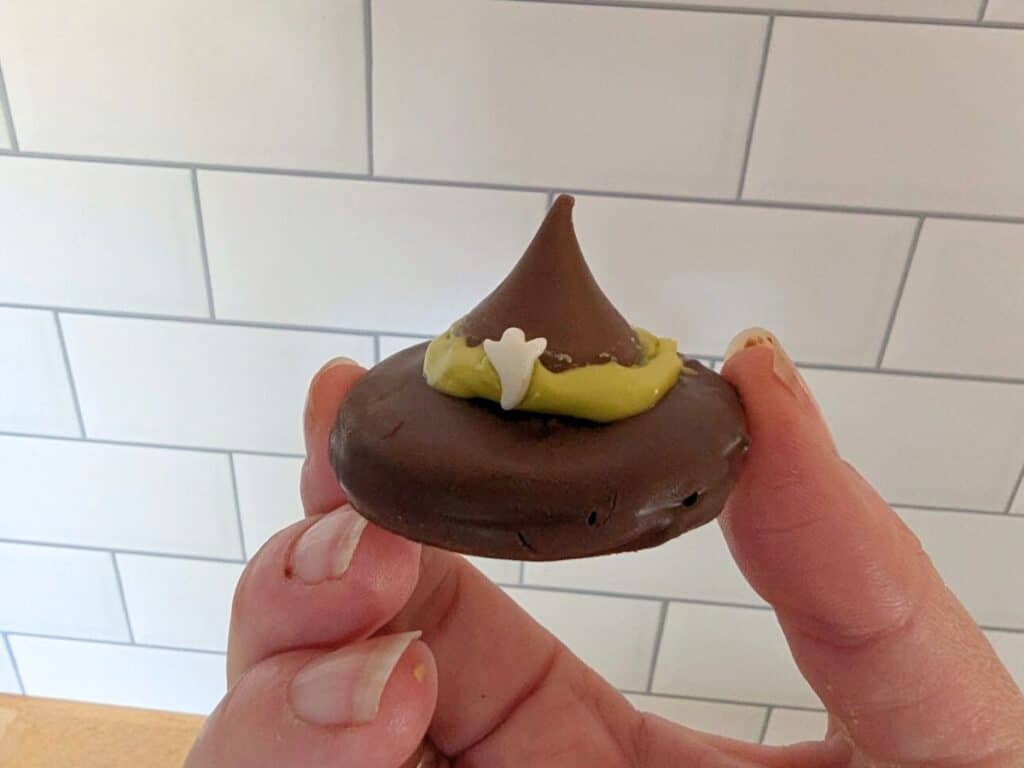 Image shows a Hand holding up a single no bake witch hat cookie.